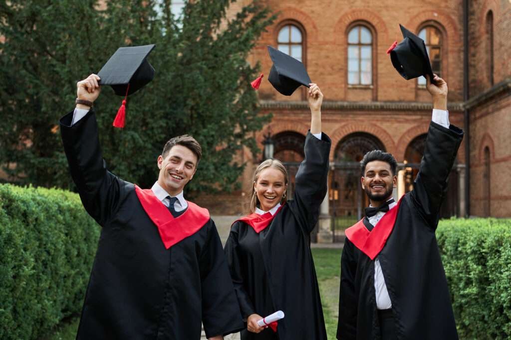 Students celebrating their graduation with smiling faces throwing hats in the air